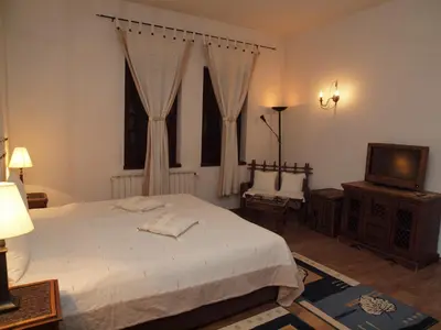 a bedroom with a white bed and a television at Momini Dvori Boutique Guest House in Bansko