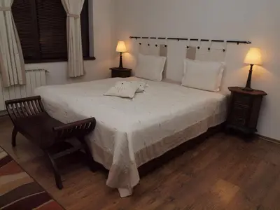 a bedroom with a large bed with a chair and two lamps at Momini Dvori Boutique Guest House in Bansko