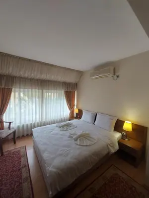 a bedroom with a bed with white sheets and a window at Elegant Complex in Pazardzhik