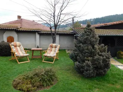 two chairs and a table in a yard at Family Vacation Home Topolnitza in Koprivshtitsa