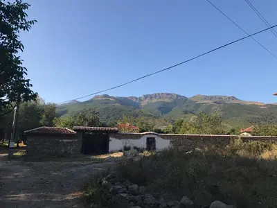 a stone building with mountains in the background at Guesthouse Planinsko Gnezdo in Tŭzha