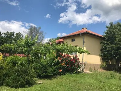 a house with a bunch of flowers in the yard at Guesthouse Planinsko Gnezdo in Tŭzha