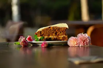 a piece of cake on a plate on a table with flowers at PinusVillas Private Jacuzzi & Phyto-Sauna in Zheleznitsa