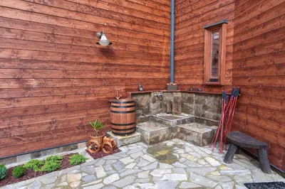 a wooden wall with a barrel and a stone patio at PinusVillas Private Jacuzzi & Phyto-Sauna in Zheleznitsa