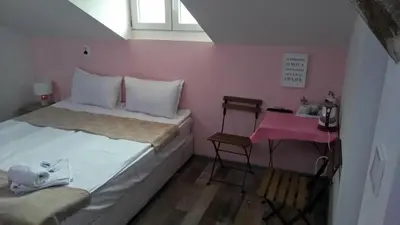 a small bedroom with a bed and a pink wall at Guest Rooms Filipopol in Plovdiv
