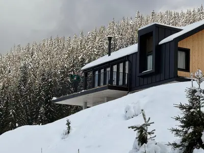 a black house on top of a snow covered hill at High Five Villas in Pamporovo