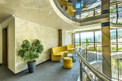 a living room with a yellow chair and a balcony at SPA Hotel Infinity Park Velingrad in Velingrad