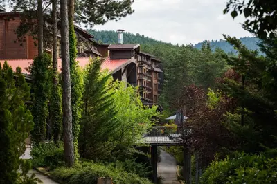 a bridge over a river in front of a building at Maxi Park Hotel & Spa in Velingrad