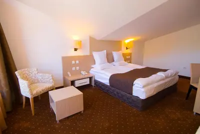 a hotel room with a large bed and a chair at Radina's Way Hotel in Borovets