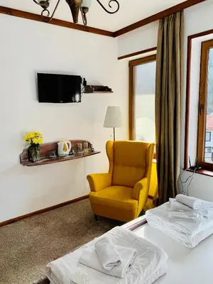 a hotel room with a yellow chair and a tv at Guest House Holiday in Melnik in Melnik