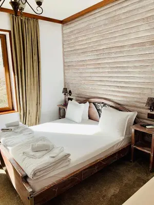 a bedroom with a large bed with white sheets at Guest House Holiday in Melnik in Melnik
