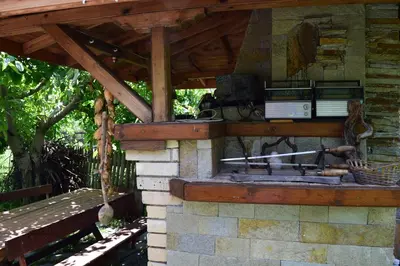 a stone outdoor fireplace with a wooden roof at Villa Kabasanov in Smolyan