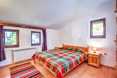 a bedroom with a bed and two windows at Hotel Kalina in Shiroka Lŭka