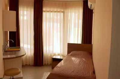 a bedroom with a bed and a desk and curtains at Апарт Център Apart Center in Plovdiv