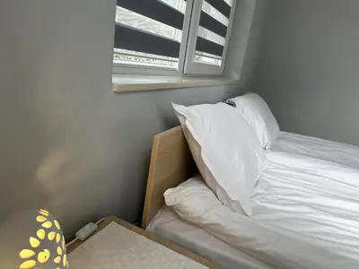 a bed with white sheets and a window in a room at Saint Maria Guest House in Velingrad
