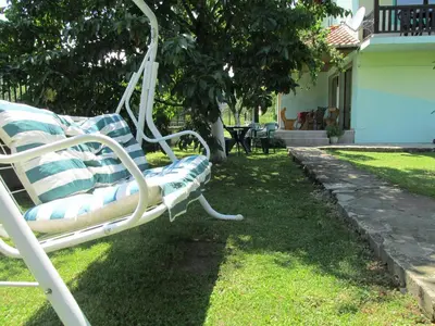 a white bench sitting in the grass next to a house at Pri Orehite Guesthouse in Oreshak