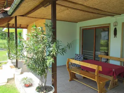 a porch with a wooden bench and a tree at Pri Orehite Guesthouse in Oreshak