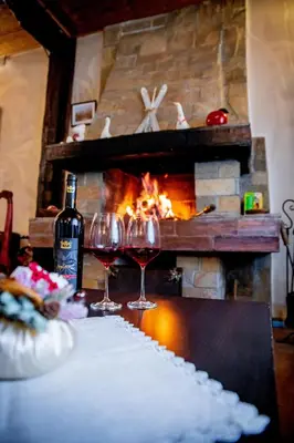 two glasses of wine sitting on a table in front of a fireplace at Velinov Boutique Hotel with Free Shuttle in Bansko