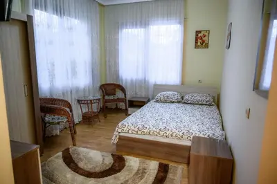 a bedroom with a bed and a table and windows at Guest House Angelkovi in Sapareva Banya