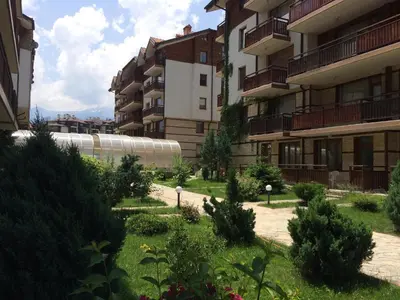 a courtyard of a building with bushes and trees at Apartments Four Leaf Clover Bansko to rent in Bansko
