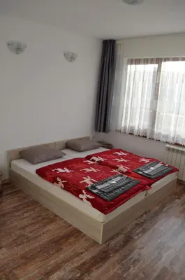 a bed with a red blanket on top of it at EldoSport Hotel in Dospat