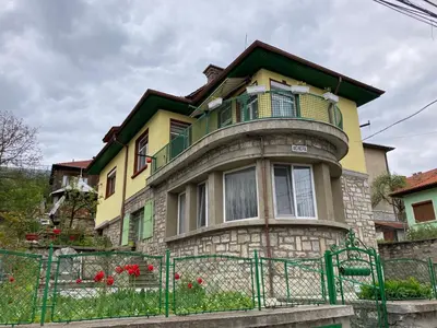a yellow and green house with a balcony at Vila Venera in Velingrad