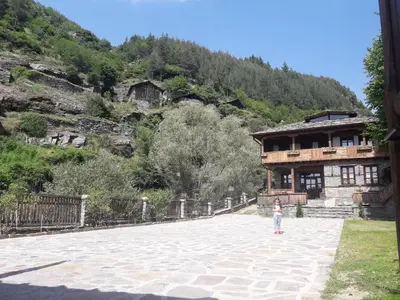 a little girl standing in front of a building at Kyshta za Gosti Gospodevi in Gorno Dryanovo