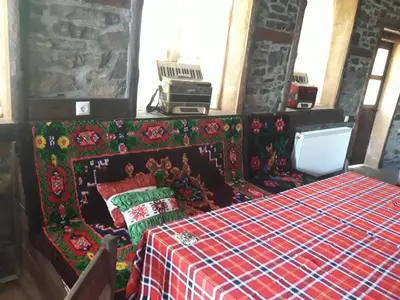 a bedroom with a bed with a red and green blanket at Kyshta za Gosti Gospodevi in Gorno Dryanovo