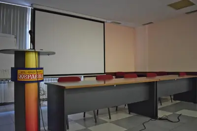 a classroom with desks and red chairs and a large screen at Hotel Jeravna in Bankya