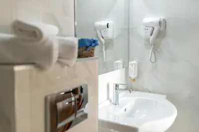 a white bathroom with a sink and a mirror at Spa Hotel Spartak in Sandanski