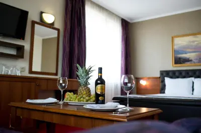 a room with a table with a bottle of wine and wine glasses at Spa Hotel Spartak in Sandanski
