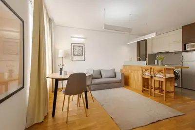a living room with a table and a couch and a kitchen at Deluxe Studio Studentski Grad in Sofia