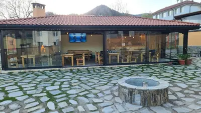 a pavilion with a table and chairs and a tree stump at Guesthouse Nefertiti in Smolyan