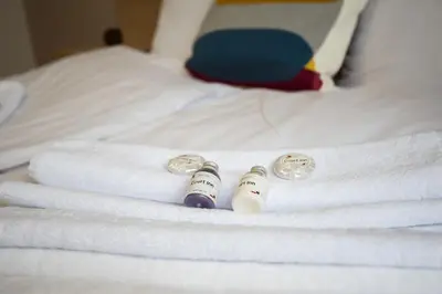 a bed with white towels and two bottles on it at Court Inn in Panagyurishte