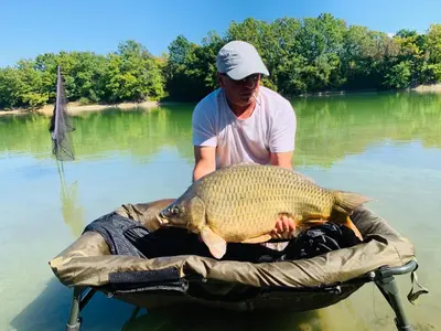 a man holding a large fish in the water at Комплекс язовир Валтата Komplex yazovir VALTATA in Samuilovo