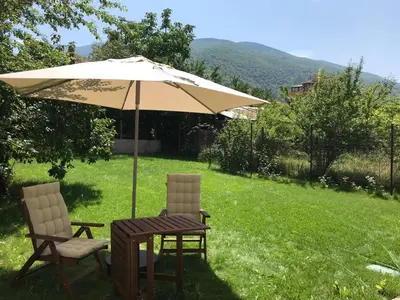 a table and two chairs under an umbrella in a yard at Guest House Vergie, Fully Private in Sapareva Banya