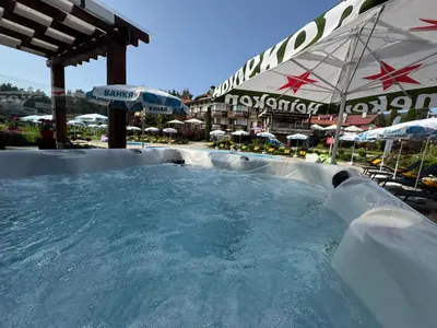 a large plunge pool in a resort with an umbrella at Family Hotel Eterno in Tsigov Chark