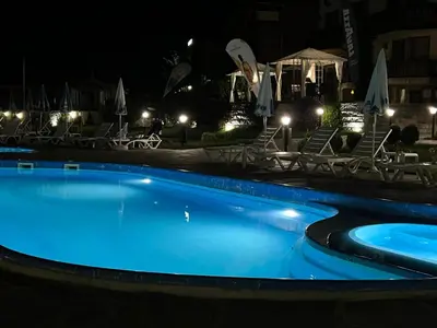 a swimming pool at night with chairs and umbrellas at Family Hotel Eterno in Tsigov Chark