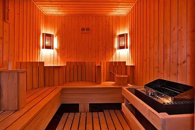 a sauna with a tub and a stove in it at Belvedere Holiday Club in Bansko