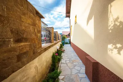 a narrow alley with a stone wall and flowers at Guest House Holiday in Ognyanovo
