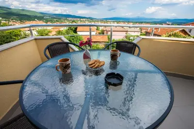 a glass table with two cups and cookies on a balcony at Guest House Holiday in Ognyanovo