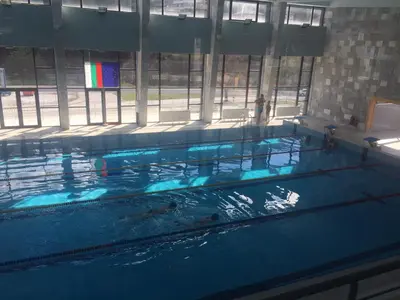 a large swimming pool with blue water in a building at Guest Apartment Monarch in Smolyan