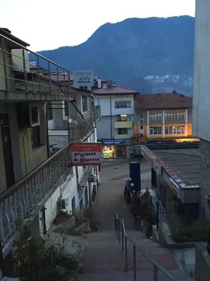 an empty street in a town with buildings and a train at Guest Apartment Monarch in Smolyan
