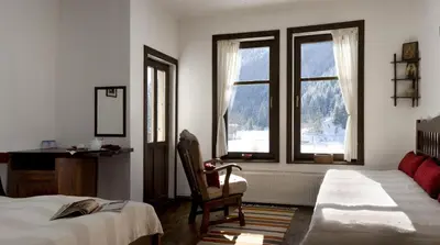 a bedroom with two beds and a desk and two windows at Family Hotel Arkan Han in Trigrad