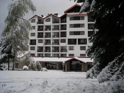 a large white building with snow on the ground at Borovets Gardens Chalet Flat in Borovets
