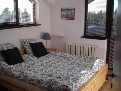 a bedroom with a bed and two windows at Borovets Gardens Chalet Flat in Borovets