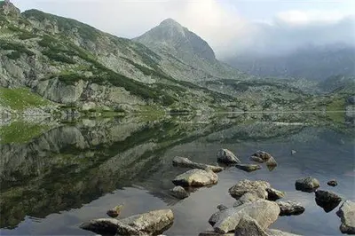 a body of water with rocks and a mountain at PM Services Sequoia Apartment in Borovets