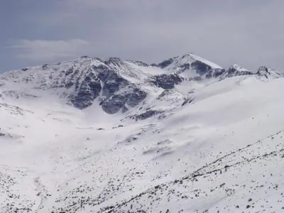 a mountain covered in snow with mountains in the background at PM Services Sequoia Apartment in Borovets
