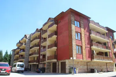 a red building with cars parked in front of it at PM Services Sequoia Apartment in Borovets