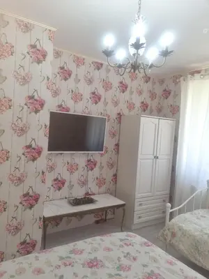 a bedroom with a tv on a wall with pink flowers at Guesthouse Jasmin in Sapareva Banya